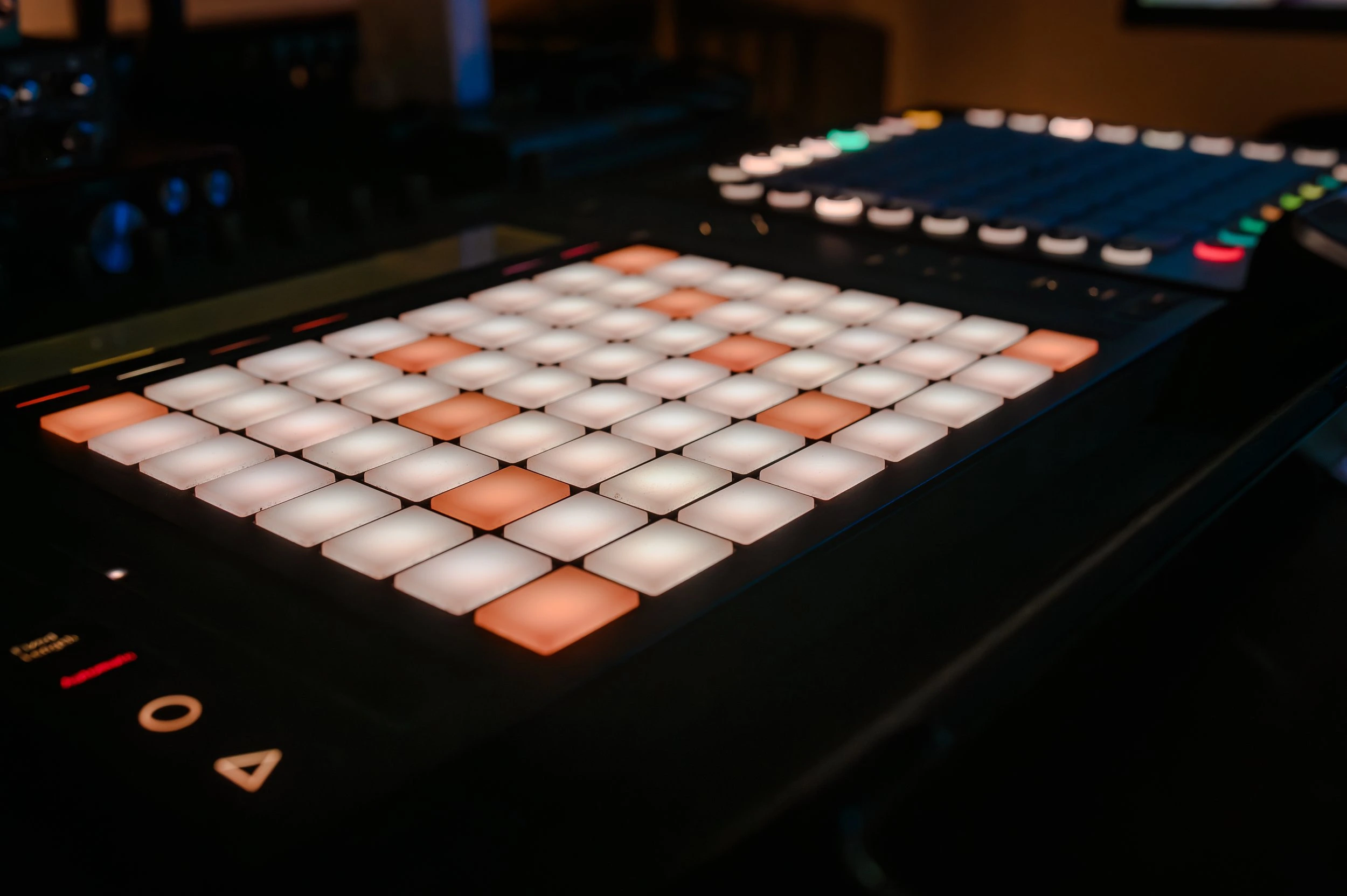 A DJ controller with illuminated pads in a dimly lit environment.