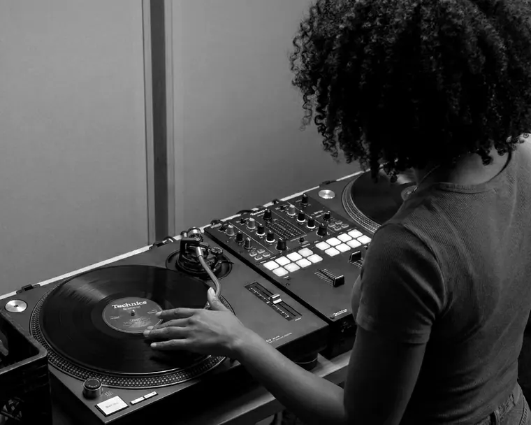 Hands on turntables and a DJ mixer in the VOYCE Academy booth