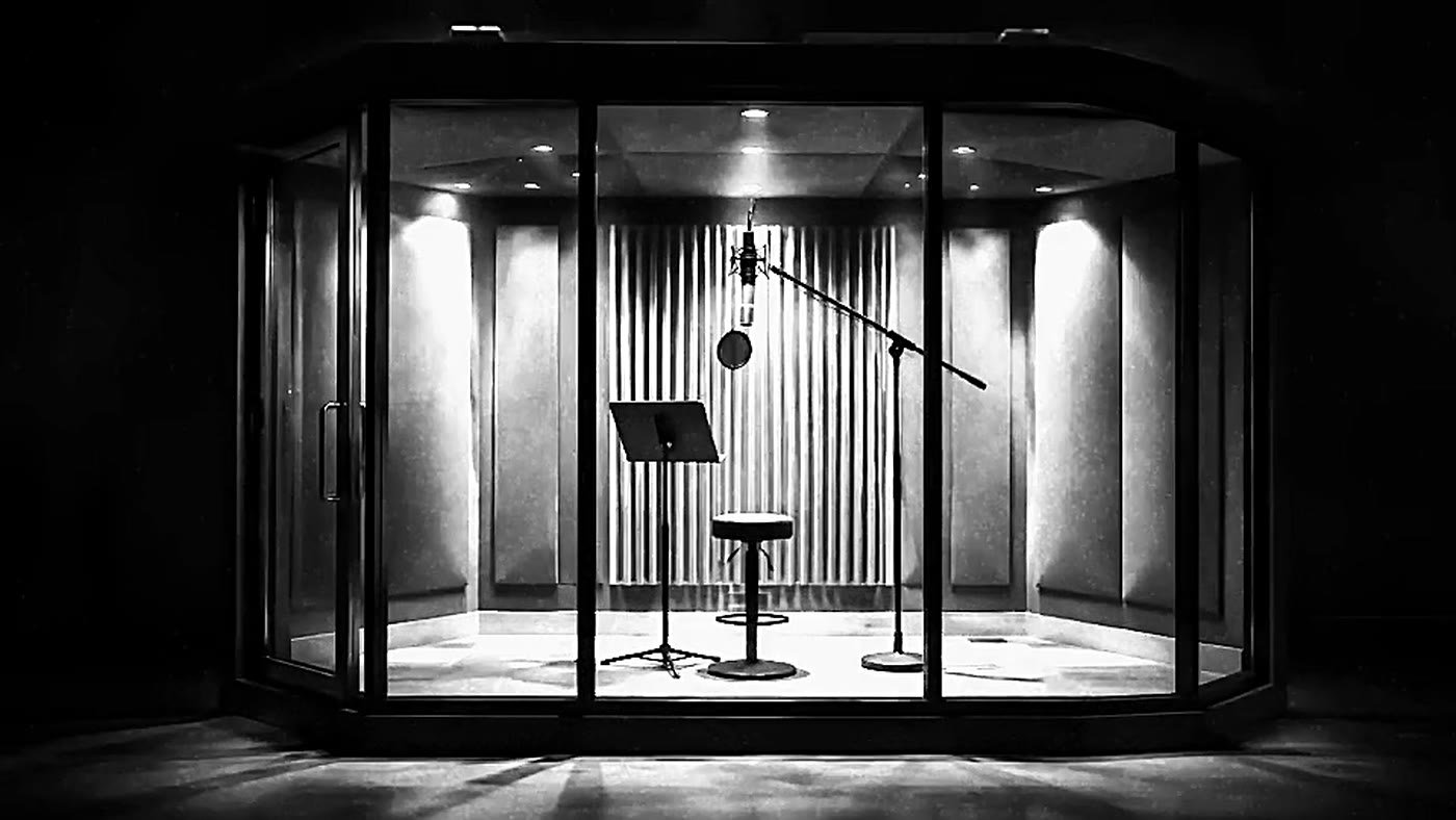 The vocal booth, acoustically treated and lit for a take.